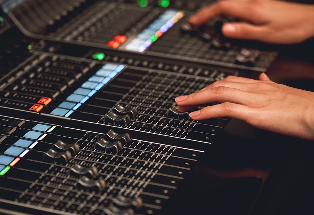 Audio system for professionals. Close-up view of sound engineer adjusting digital audio mixing console. Sound recording studio. Media production studio. Music record service